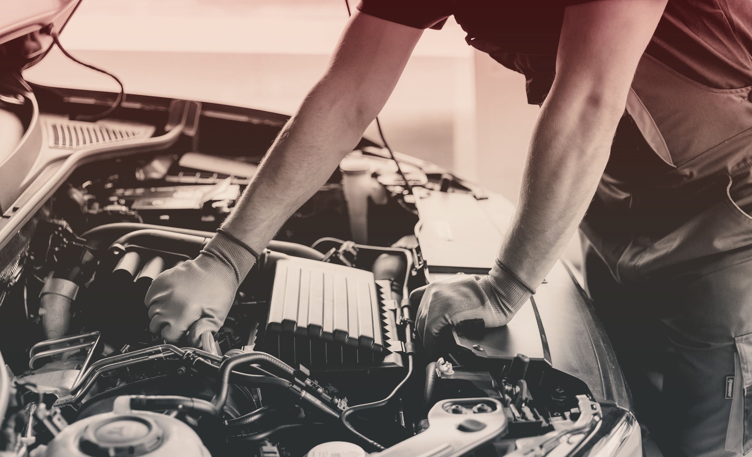 person with gloves on looking under the hood of a car